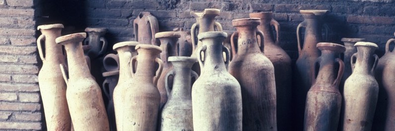 Photograph of a row of amphora resting against a wall