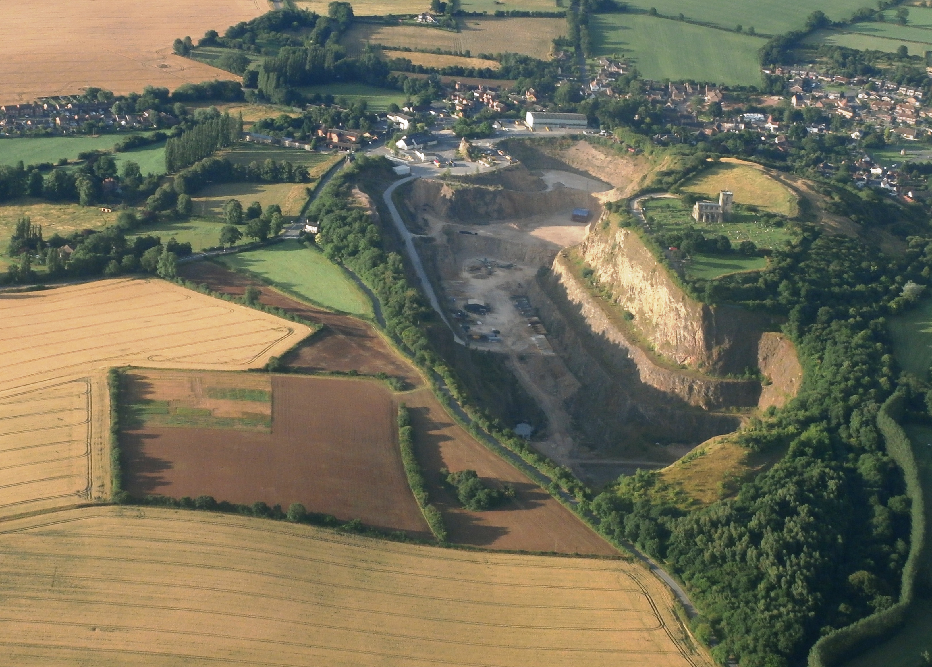 Aerial view of Breedon Hill, showing fields and the site on a hill with a large chunk missing where the quarry now islarge quarry 