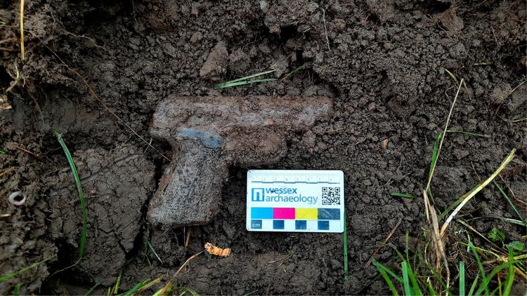 An image of a German WWII pistol covered in earth