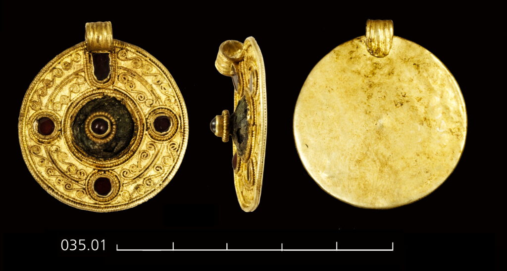A photograph of a gold pendant