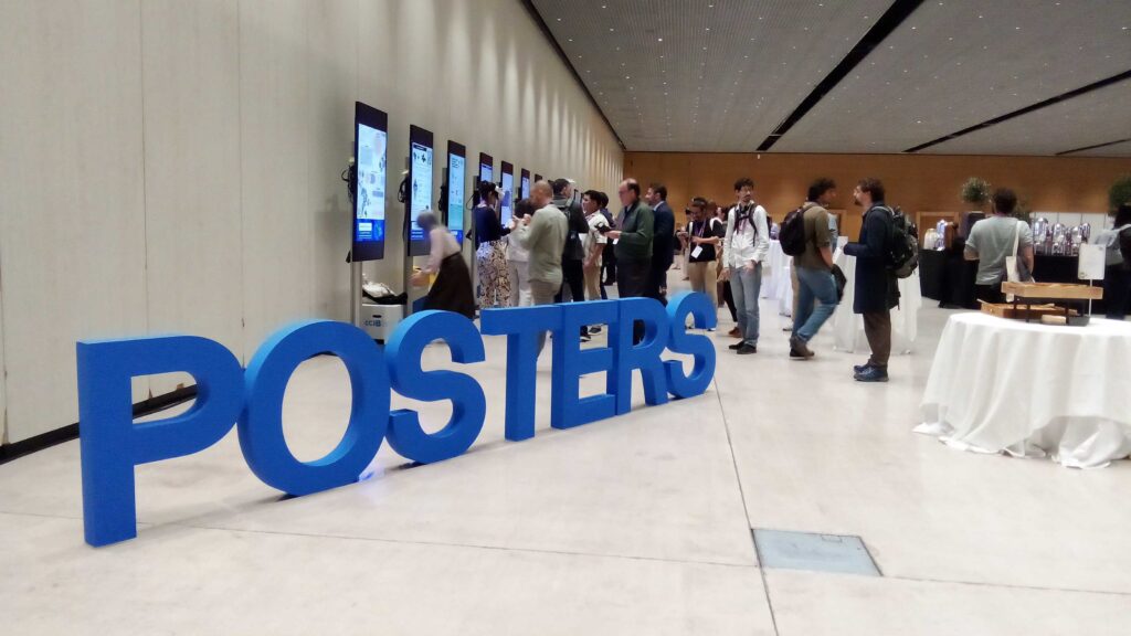 A large sign that says 'posters' with lots of attendees looking at posters in the background 