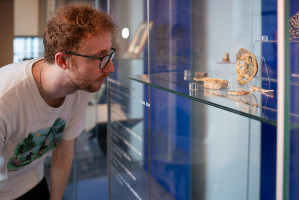 image of a student looking at artefacts in a glass cabinet