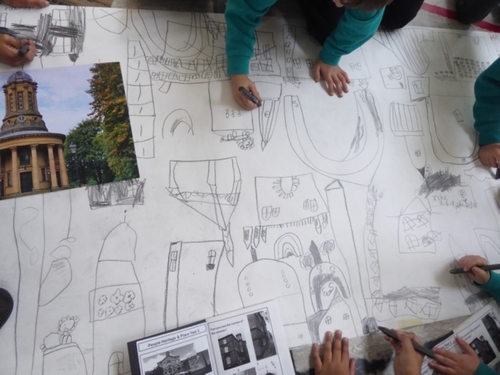AN image of pupils around a large piece of paper drawing 