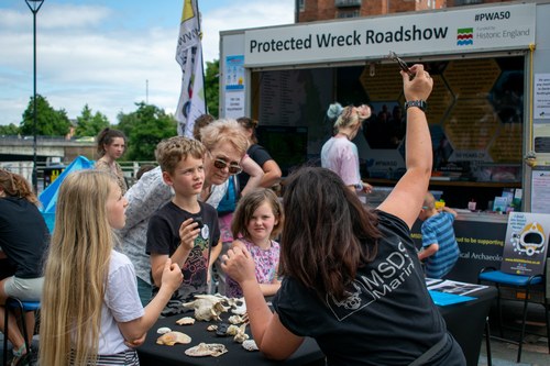 Members of the public handling archaeological objects during an outreach event. 