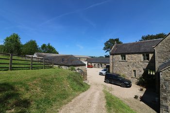 General view of the U-shaped outbuildings and the rear of the house from the southwest