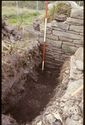 Thumbnail of 1988 photograph showing excavated rectangular feature at foot of standing wall in Cruck Building.
