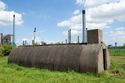 Thumbnail of 110497_HBR_Image_052, general view of an air raid shelter within the Second World War site, with an industrial power station in the background.