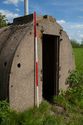 Thumbnail of 110497_HBR_Image_056, entrance to an air raid shelter within the Second World War site, with an industrial power station in the background.