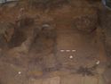 Thumbnail of General view of the chamber, following the initial block lifting of the suspended grave goods including: the hanging bowl, flagon, small cauldron &  east mediterranean basin. The photo shows the filtration deposits around the coffin, and semi-circular negative feature [251] against the north wall.
