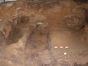 Thumbnail of General view of chamber, following the initial block lifting of the suspended grave goods. The photo shows the filtration deposits around the decayed coffin [229], and semi-circular negative feature [251] against the north wall.