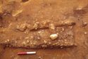 Thumbnail of Sword <s63> in situ with displaced coffin fitting <80> corroded to its upper surface (centre), 0.20m scale